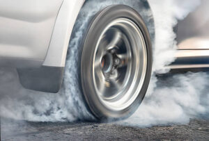 Drag racing car is burning tires at start line.