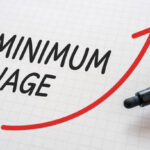White paper written "MINIMUM WAGE" with markers.